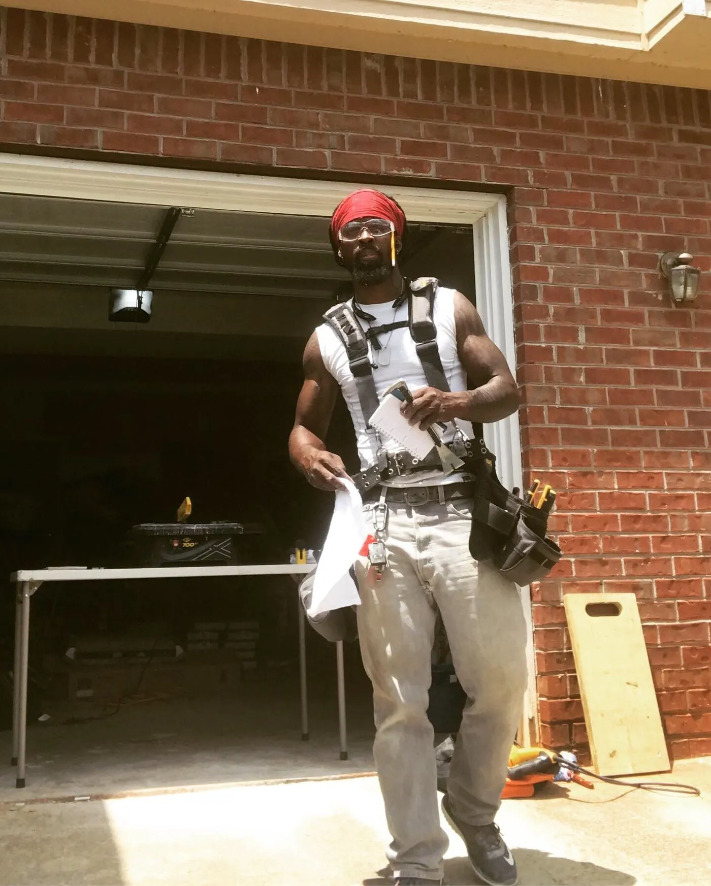 The owner in a tool belt and safety glasses walking out of a job site